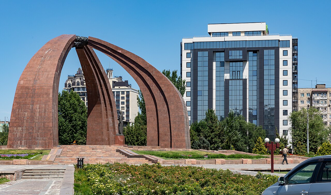 Victory Square is a public square in the city of Bishkek, the capital of Kyrgyzstan. It is dedicated to the Victory over Nazi Germany. It was created in 1984, in on the occasion of the 40th anniversary of the Liberation of the USSR.The square features a statue of a woman, waiting for her husband to return home from the war. The central area is filled with an eternal fire, The square is held together by three ribs of red granite representing a yurt.

(Wikipedia)