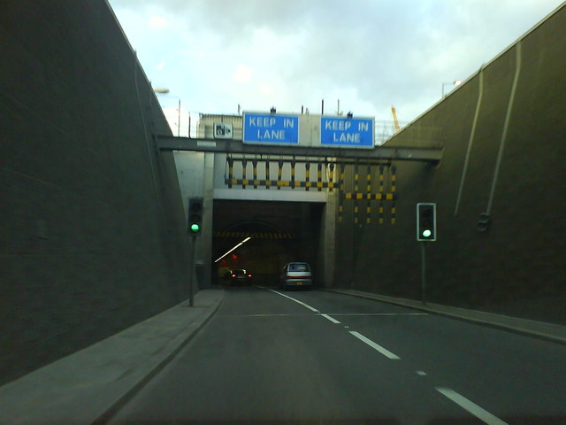 Entering the Blackwall Tunnel Northbound
This was taken from the passenger seat of a car going northbound on the A102 at about 30mph. The black and yellow pendulums are intended to prevent overheight vehicles getting in, but amazingly they still manage to get in from time to time. It then causes utter chaos for hours and for miles around.