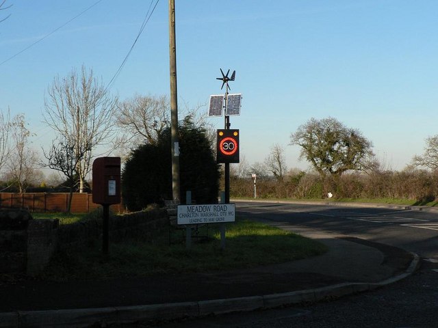 Charlton Marshall: postbox № DT11 29 The postbox is emptied finally at 11 o'clock each morning except Sunday. In the background, the speed limit sign has clocked an approaching motorist exceeding 30pmh, activating the illuminated warning.