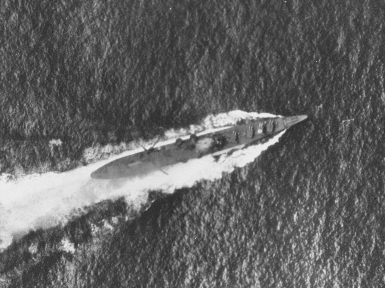 The Japanese heavy cruiser Chikuma under air attack during the Battle of the Santa Cruz Islands, 26 October 1942. Note the smoke coming from her bridge area, which had been hit by a bomb, and what appears to be a recognition marking painted atop her number two eight-inch gun turret. The ship's catapults and aircraft crane appear to be swung out over her sides, aft of amidships.The original photograph came from Rear Admiral Samuel Eliot Morison's World War II history project working files.