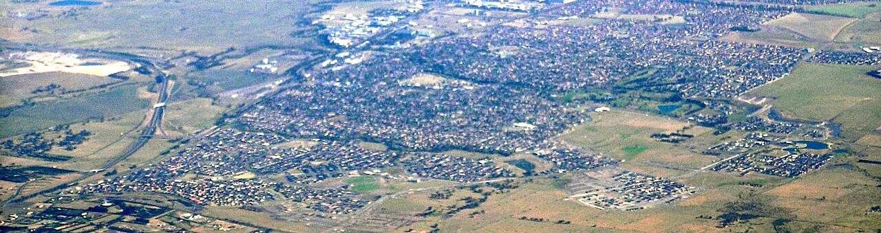 Craigiburn Victoria from north west, Hume highway is on the left, and curves off into the Craigieburn bypass.  The Crigieburn Public golf course is prominent in the right of centre, it is on the banks of the Aitken Creek.  The reserve Bank note printing factory, in Craigieburn, is the bunch of white buildings on the top, left of the midline