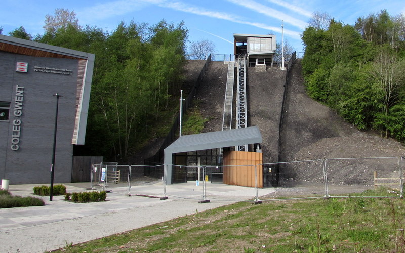 This is an image of the Ebbw Vale Cableway just before opening. Viewed from Lime Avenue. Not yet open in mid May 2015, the £2.5 million Mechanical Link is part of the Ebbw Vale Town Regeneration Programme. It is a cableway system between the former steelworks site (now occupied by a college campus, a school and the newly-opened Ebbw Vale Town railway station) up to the edge of the A4046. A cabin holding about 20 people (weight limit 1,850 kg) will provide an easy and efficient pedestrian link to and from the town centre. The track is c47m long and rises c23m. Each journey will take about three minutes.