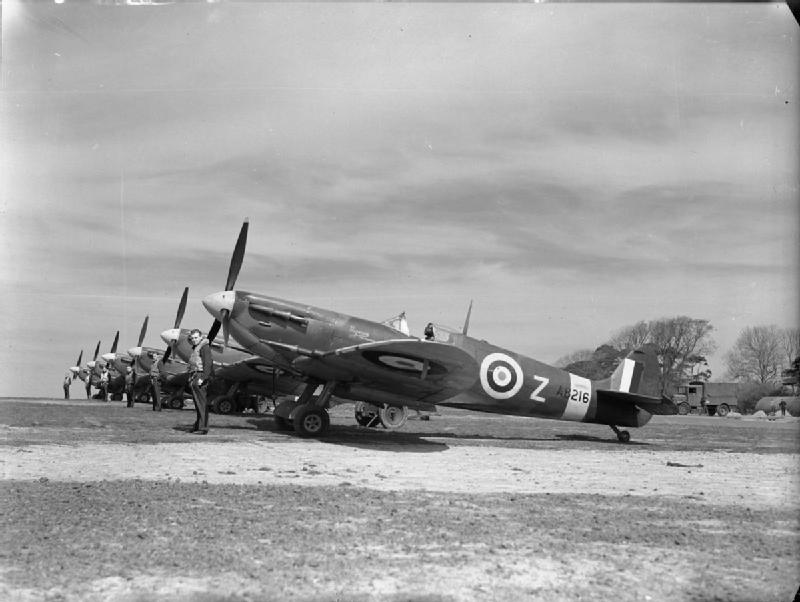 Aircraft of the Royal Air Force, 1939-1945- Supermarine Spitfire.
Spitfire Mk Vs of No. 91 Squadron lined up at Hawkinge, May 1942.  Standing nearest the camera is the Squadrons Commanding Officer, Squadron Leader R W Oxspring, in front of his personal aircraft, a Mark VC, AB216: DL-Z.  Next to him, in front of another Mark VC, is the 'B' Flight commander, Flight-Lieutenant F H Silk.  The remaining aircraft are Mark VBs