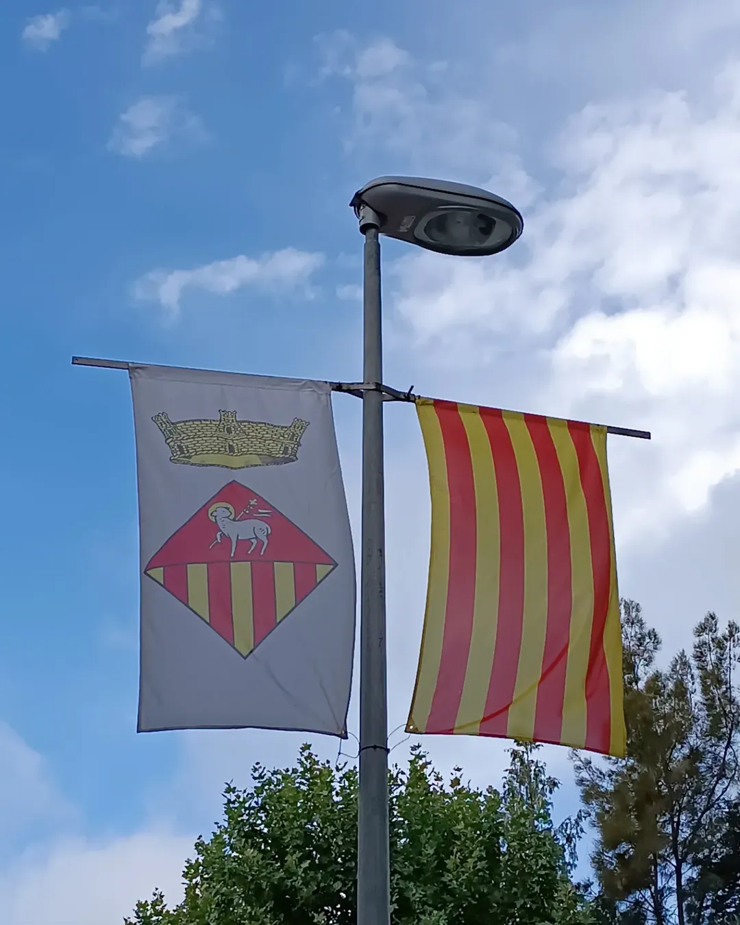 Escudo de Matadepera y la bandera de Cataluña adornando una farola para la fiesta mayor de 2025.