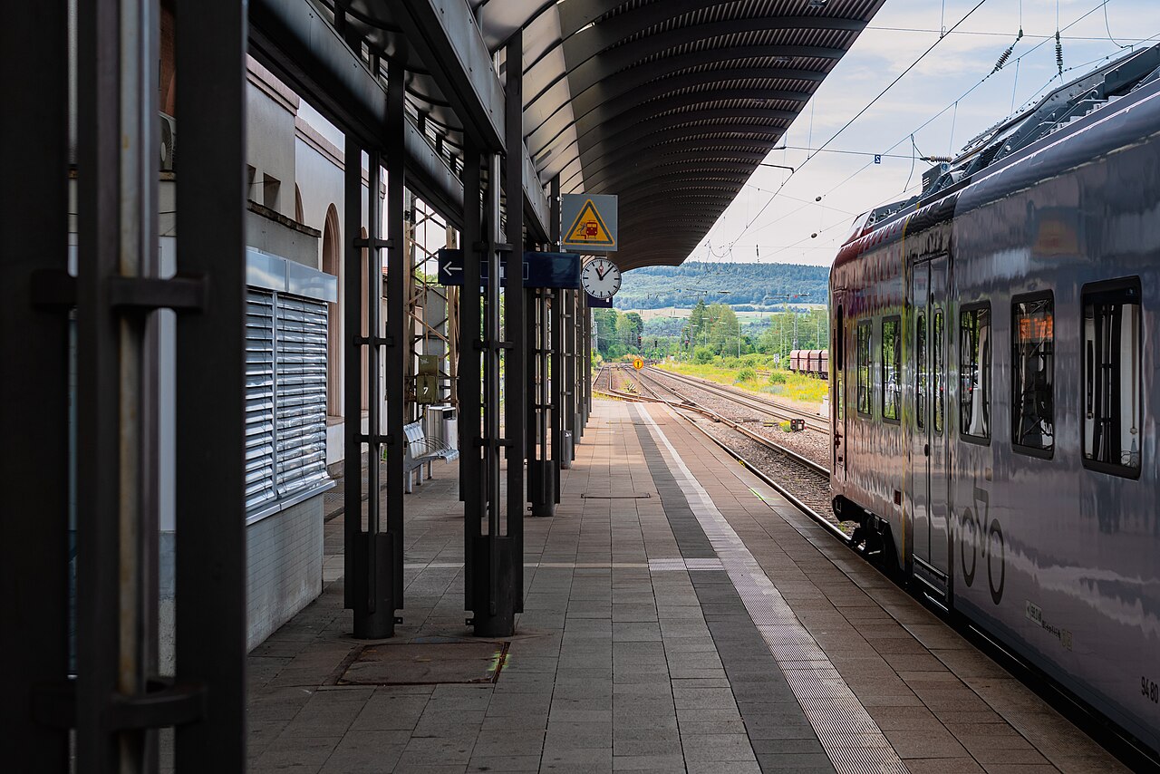 A platform of the train station Merzig (Saar) with standing regional train. The clock at the plattform shows the time 11:07.