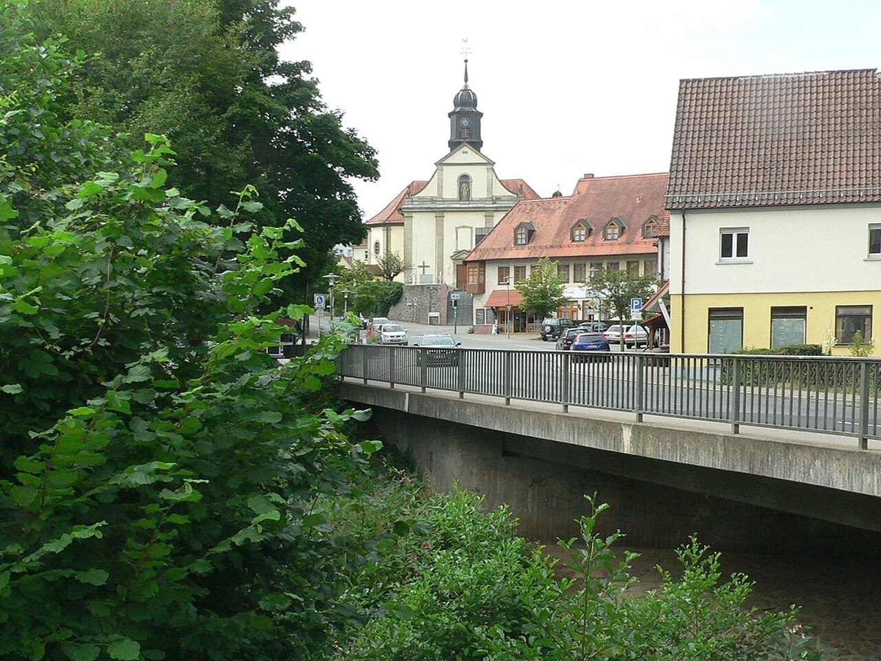 Mömbris: In the foreground the bridge across the river Kahl, in the middle the central square called "Am Markt" and behind the parish church.