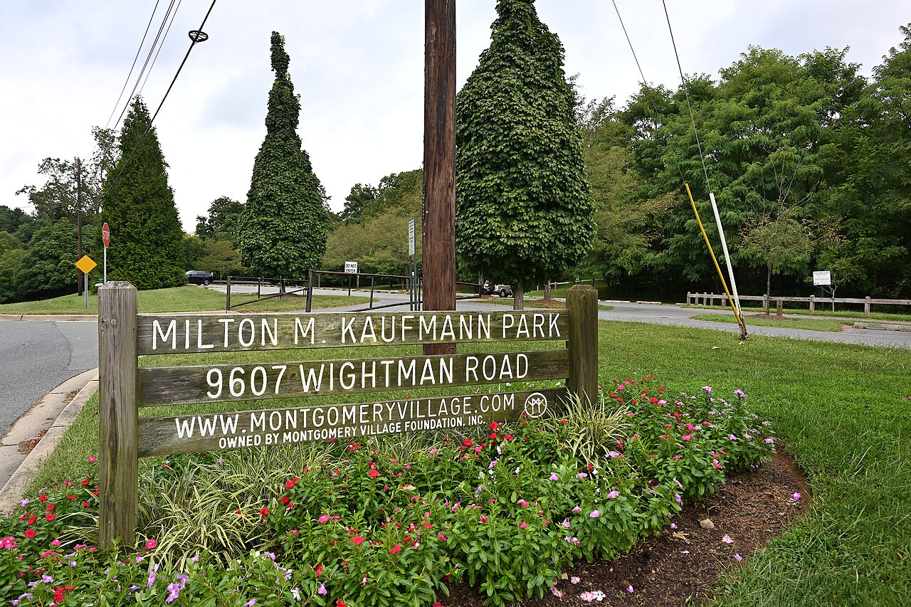 The sign for the Milton M. Kaufmann Park with flowers planted around it and the parking lot in the background. 9607 Wightman Road, Montgomery Village, Maryland 20879.