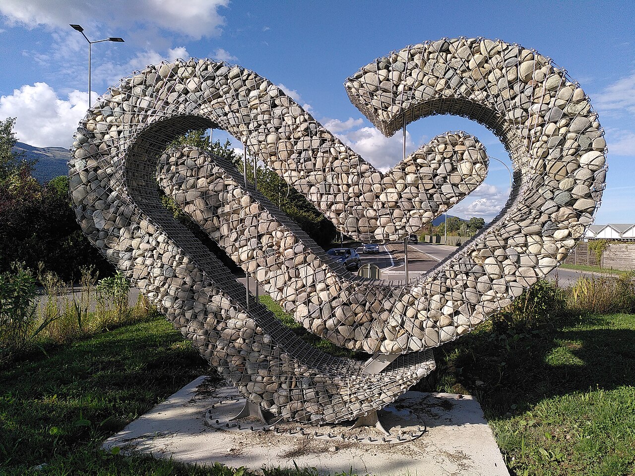 Photos du rond-point rue de la faucille, à St.-Genis-Pouilly, montrant la sculpture "Saint-Genis, un coeur de pierre", d'un artiste inconnu, qui dénonce la bétonisation galopante de la commune ces dernières années. Prises fin d'après-midi, journée ensoleillée, sous différentes angles en septembre 2025.