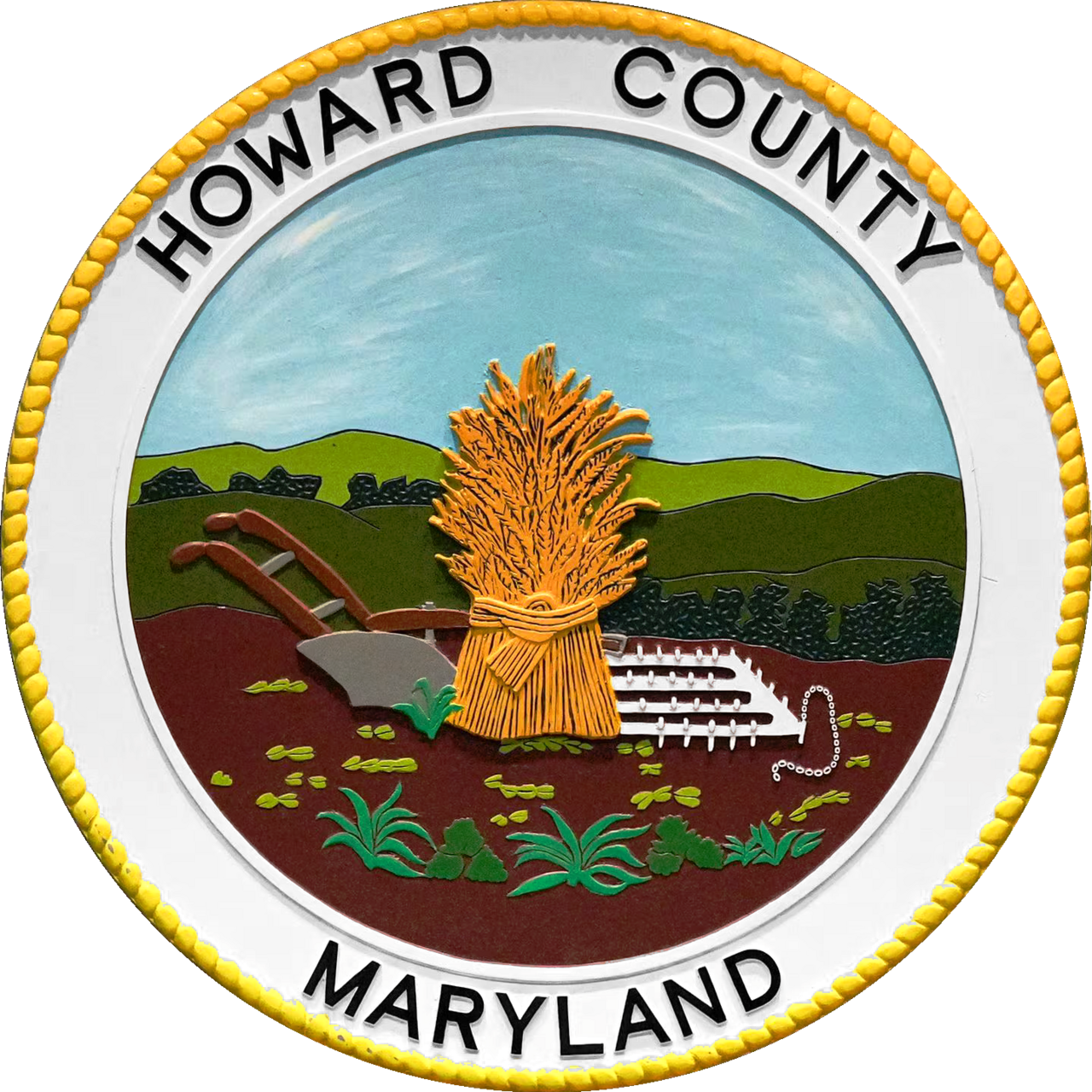 The seal of Howard County, Maryland. The Howard County Seal was designed and approved on behalf of the Howard District of Anne Arundel County in 1840, but the County was not officially established until Howard District was separated from Anne Arundel County in 1851. The seal was designed by Edward Stabler, one of the foremost seal designers of the time (He also designed seals for Anne Arundel County). 
The Howard County Code of 1977 stipulates that the seal of the county shall be a copy of the seal designed by Edward Stabler in 1840. The seal depicts "a shock of wheat, centrally dominant, with a hand plow to the left, and a spike harrow to the right. All three (3) are centered on a plowed field with tobacco plants growing in the foreground. Trees and rolling hills form the background, and a cloudless sky forms the upper third of the design." 

The County Code describes the colors that are to be used when the seal is rendered in color. The sky--Prussian blue-med.; the wheat--yellow ochre; the hills--graduated shades of teraverte; the tobacco plant in the foreground--Chrome green-med.; the trees--a dark shade of chrome green; the soil--burnt umber-med;.; the spike harrow and the plow blade--Ivory black diluted to gray; and the plow handles--Burnt sienna-med.