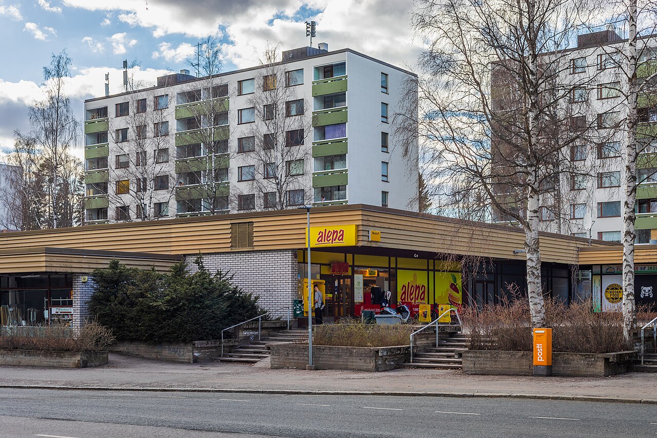 Rajatorppa shopping centre (Rajatorpan ostoskeskus) and apartment buildings from the 1970's in Vapaala, Vantaa, Finland in 2023 April. The shopping centre was built in 1972. The apartment buildings of Piikkikuja 3 were built in 1972 as well. The road below is Nuijatie.