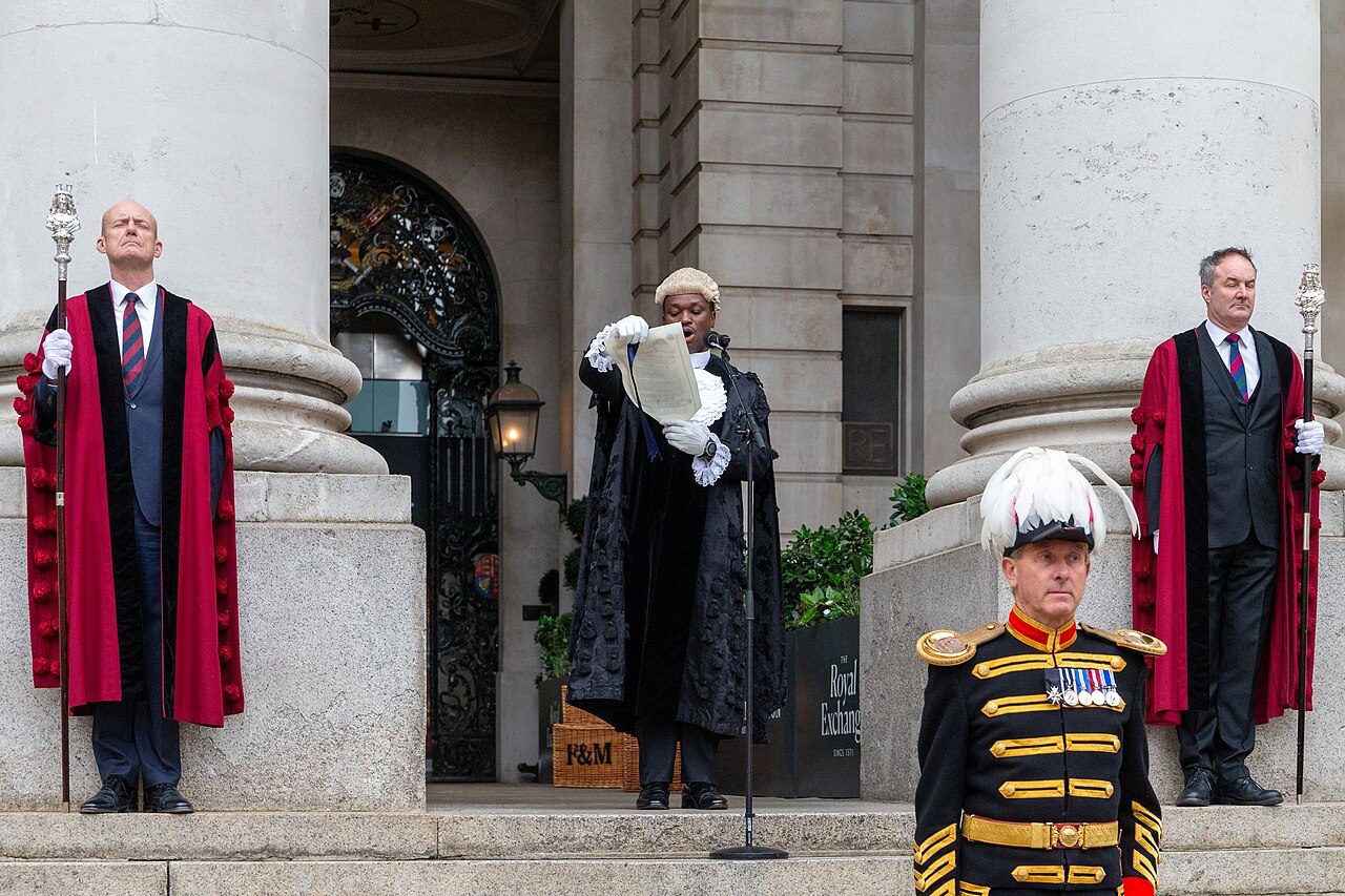 Common Cryer and Serjeant-at-Arms of the City of London Major Peter Oweh reading the Royal Proclamation announcing the dissolution of the Parliament of the United Kingdom, flanked by two Constables of The Royal Exchange with silver topped Mercers Company staves. The City Marshal of the City of London Philip Jordan can be seen in front towards the bottom of the steps.