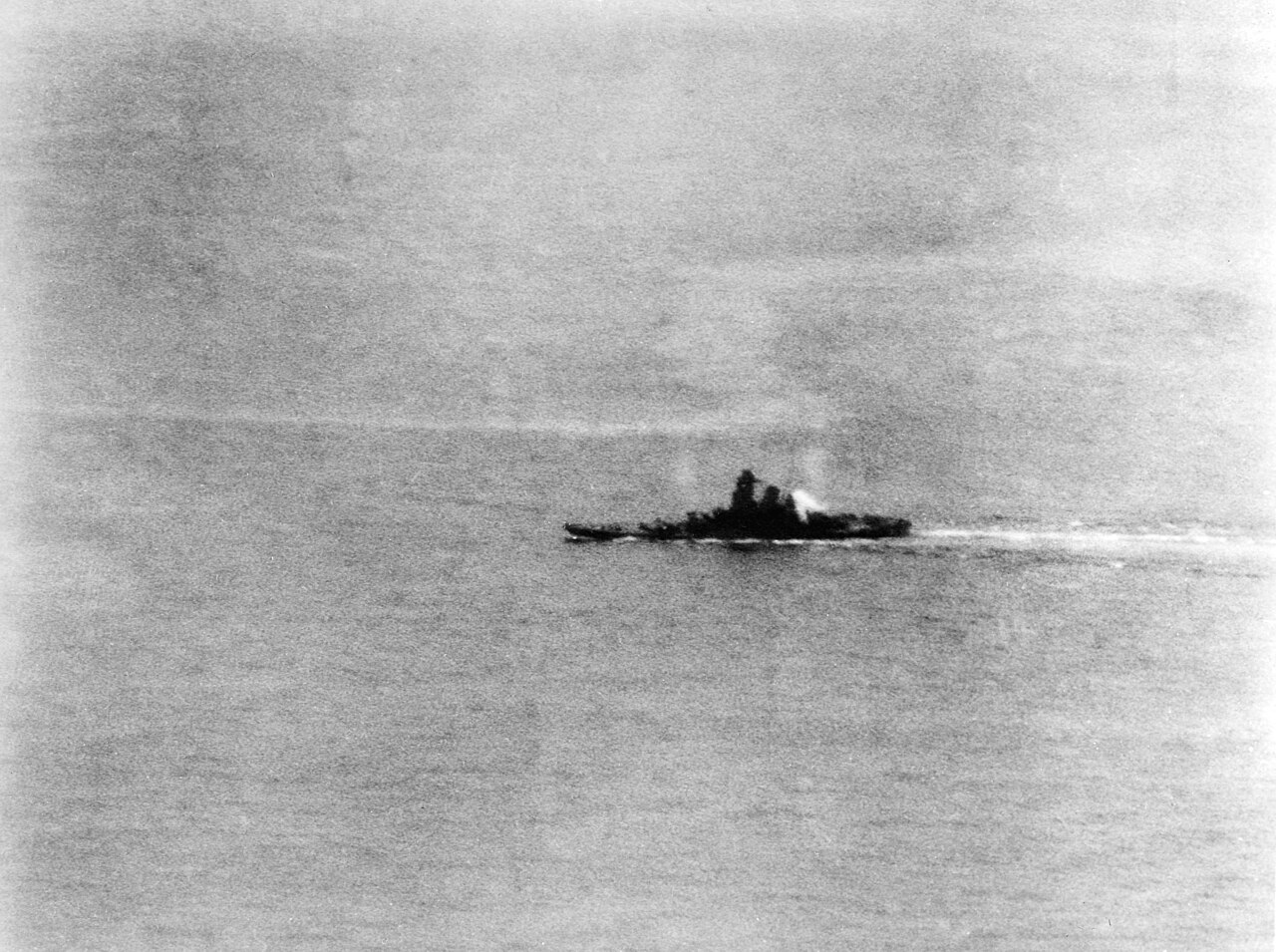 Operation "Ten-Go": The Japanese battleship Yamato listing to port and afire at the after end of her superstructure, but still underway, while under attack by U.S. Navy carrier planes north of Okinawa, 7 April 1945. The photo was taken by a plane from the aoircraft carrier USS Yorktown (CV-10).
The original photo caption reads: "A torpedo plane's view of battleship Yamato. This is how Japan's mightiest warship appeared as six lone U.S. Navy torpedo planes raced in to destroy her. She is still making 10 to 15 knots, though fires continue to burn amidships." (Collection of Fleet Admiral Chester W. Nimitz, USN).