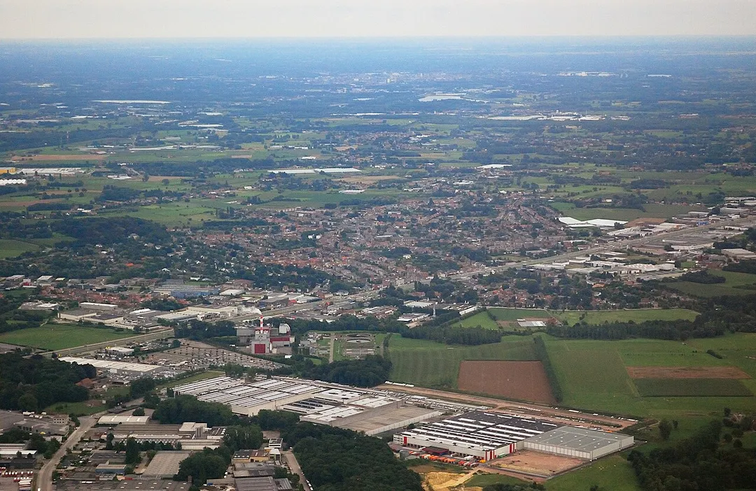 Aerial photograph of the village of Aartselaar in the province of Antwerp, Belgium. In the centre of the background the city of Mechelen can be distinguished. Nikon D60 f=55mm f/5.6 at 1/640s ISO 800. Contrast and colours enhanced using Nikon NX Studio 1.3.2. Framed and sharpened using GIMP 2.10.34.