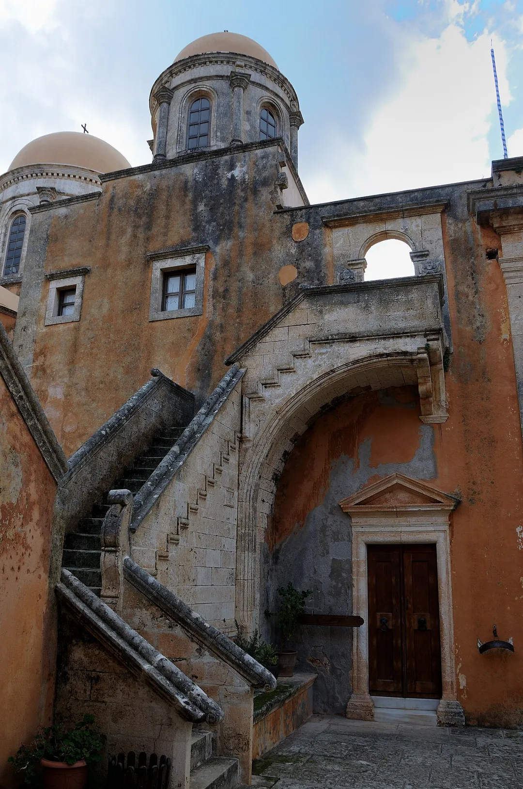 Side facade of the main church of Agia Triada Tsangarolon, with an exterior staircase and the drum of the dome.