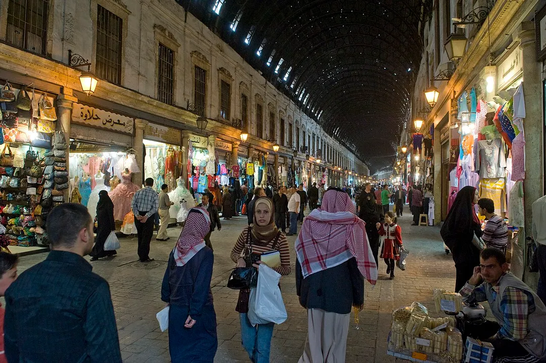 One of a set of pictures of this grand souq, some of its general appearance, some of architectural elements, some of the goods on sale. 
This سوق الحميدية is a bazar street that is special because it is on a grand scale, it has a grander aspect than the other suqs, which have longer histories, are more intimate. It was built under the Ottoman Sultan Abd al-Hamid II (1876-1909), following a former Roman axis, that probably connected to the western side of the temple of Jupiter, where we now find the Umayyad Mosque. That roman area had deteriorated. The originally wooden roof of the suq has been replaced in 1912 by a metal one.