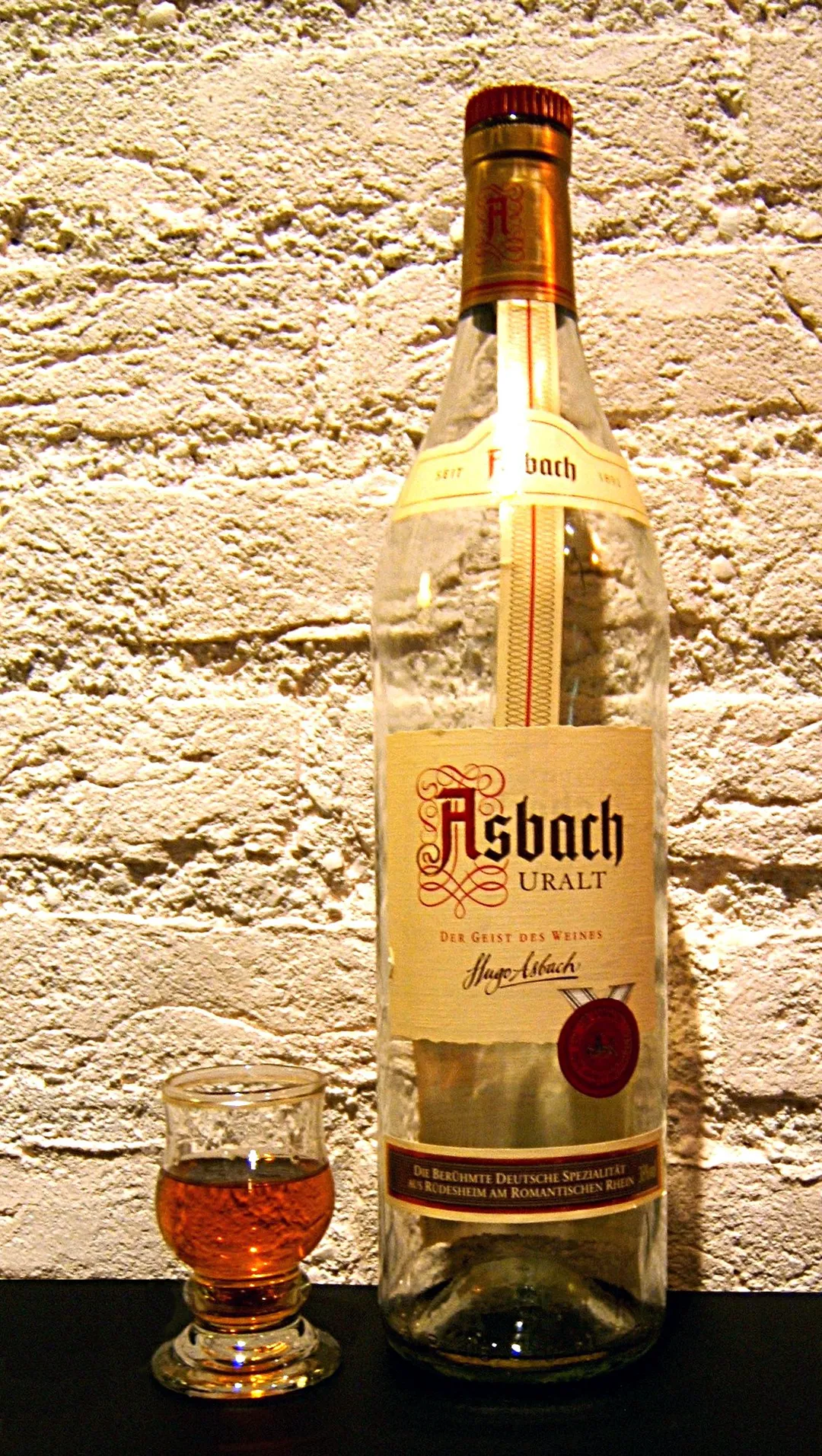 Asbach Uralt, lege fles, glas half vol