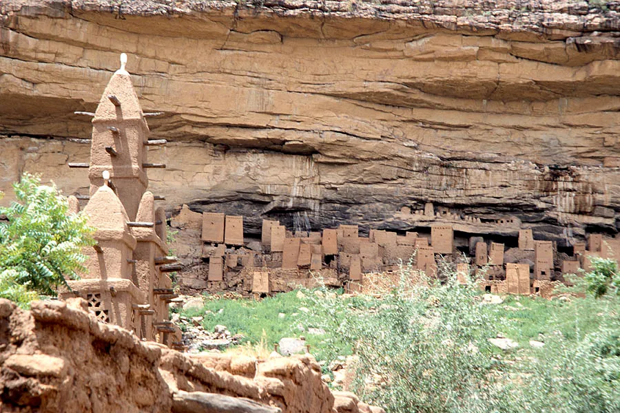 Background: the remnant of the dwelling of the ancient Tellem people by the Bandiagara Escarpment, Dogon country, Mali. *Foreground: a mud mosque of the modern-day Dogon people