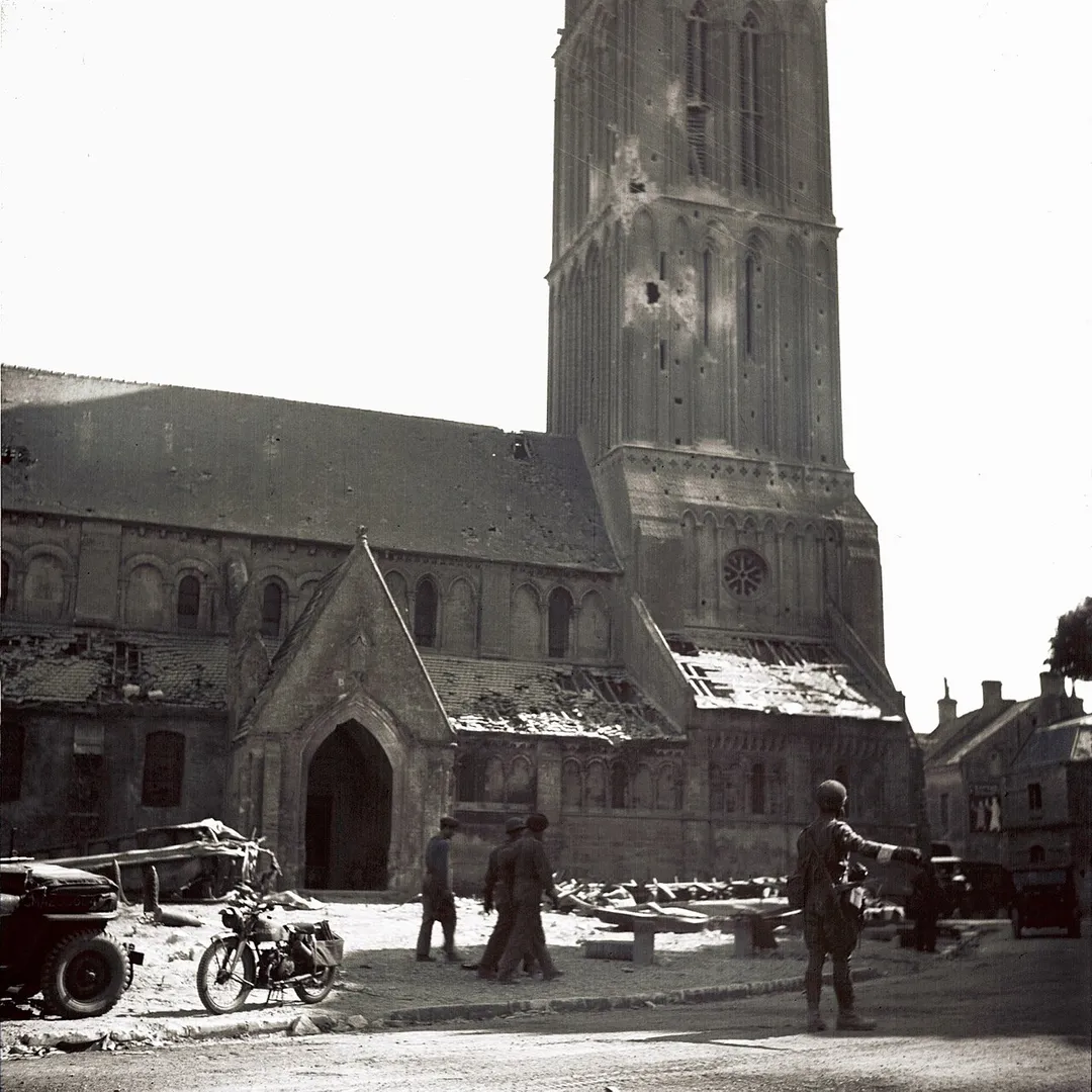 Ce soldat canadien fait la circulation dans les rues de Bernières-sur-Mer. L'église a été touché par quelques tirs d'obus. Le clocher possède deux impacts d'obus, et la toiture des dépendances est endommagée. Juno Beach.