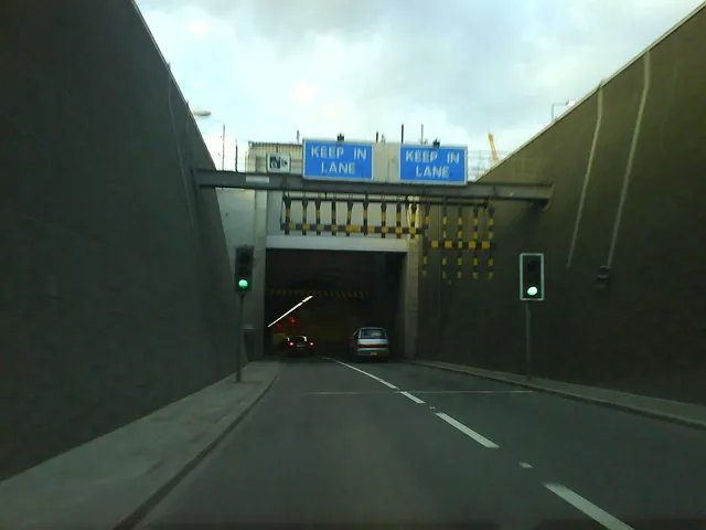 Entering the Blackwall Tunnel Northbound
This was taken from the passenger seat of a car going northbound on the A102 at about 30mph. The black and yellow pendulums are intended to prevent overheight vehicles getting in, but amazingly they still manage to get in from time to time. It then causes utter chaos for hours and for miles around.