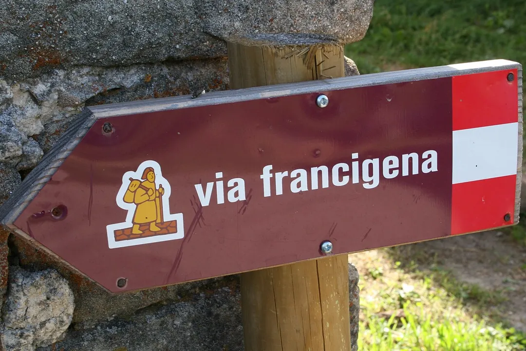A sign showing the way of the Via Francigena in Italy. This particular sign is located in Valdena, a frazione of Borgo Val di Taro.