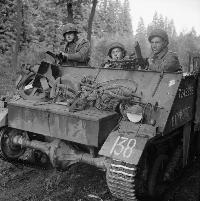 IWM caption : THE BRITISH ARMY IN NORTH-WEST EUROPE 1944-45; A Loyd carrier and crew of 15th (Scottish) Division.
Comment : The vehicle has Dutch army marking, and the men are more likely of the Royal Netherlands Motorized Infantry Brigade.

Comment : IWM caption to this image is incorrect. The formation sign on the Loyd Carrier is the Dutch Lion, in gold, holding a sword in one hand and a bundle of arrows in the other, and wearing a crown. The formation badge of the 15th Scottish Division was a red lion, on yellow background, in a white circle, on a black square. The two formation signs are very different. Further, the Arm of Service Number on the right mudguard is 138 on a green over blue square.  That is the AoS of the 1st Dutch Reconnaissance Sqn, Royal Netherlands Motorized Infantry Brigade, whereas if it was the 15th Division, it would be a 41 on a green over blue Square, signifying the 15th Scottish Reconnaissance Regiment. So there is no doubt as to the identity of the unit and formation of the Loyd Carrier, it belongs to the   Royal Netherlands Motorized Infantry Brigade.]]. The IWM as been notified of the error.