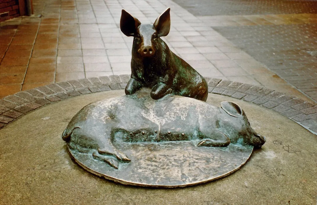 Bronze sculpture of pigs, Calne, Wiltshire, UK by artist Richard Cowdy. Installed on Phelps Parade in the 1970s.
