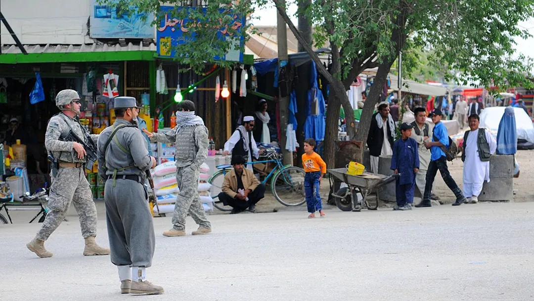 PARWAN PROVINCE, Afghanistan –U.S. Army Master Sgt. Donald Demar, non-commissioned officer in charge of Operational Coordination Center – Provincial, pulls security next to an Afghan National Police Officer on the street in Charikar outside the midwife academy, April 10. The ANP were in charge of security for a joint security effort with the Afghan National Army and U.S. Soldiers attached to the 1st Squadron, 172st Cavalry Regiment, 86th Infantry Brigade Combat Team at a graduation for 29 midwives, April 10.  (Photos by U.S. Army Staff Sgt. Whitney Hughes, Task Force Wolverine Public Affairs)