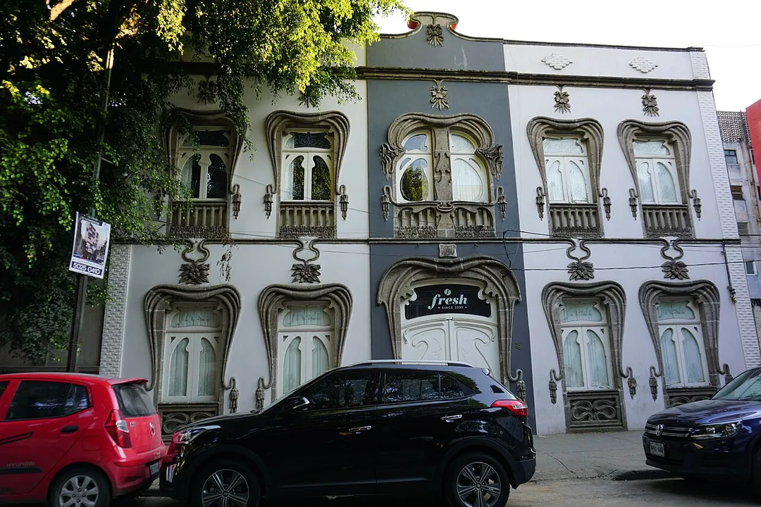 This 1916 building is described as the “best example of its kind” (Art Nouveau) in Mexico City's Roma neighbourhood by the book Ciudad de México Guía de Arquitectura / Mexico City An Architectural Guide, edited by Ernesto Alva Martinez. El Universal newspaper described it as “the only property in the Mexican capital that retains the Art Nouveau style in its entirety.” It is attributed to “Arquitectura Prunes”, as noted in the panel on the facade above the doorway. In 2006, Higuera + Sánchez architects restored the building for Grupo Pegaso, rescuing it from a state of abandonment.