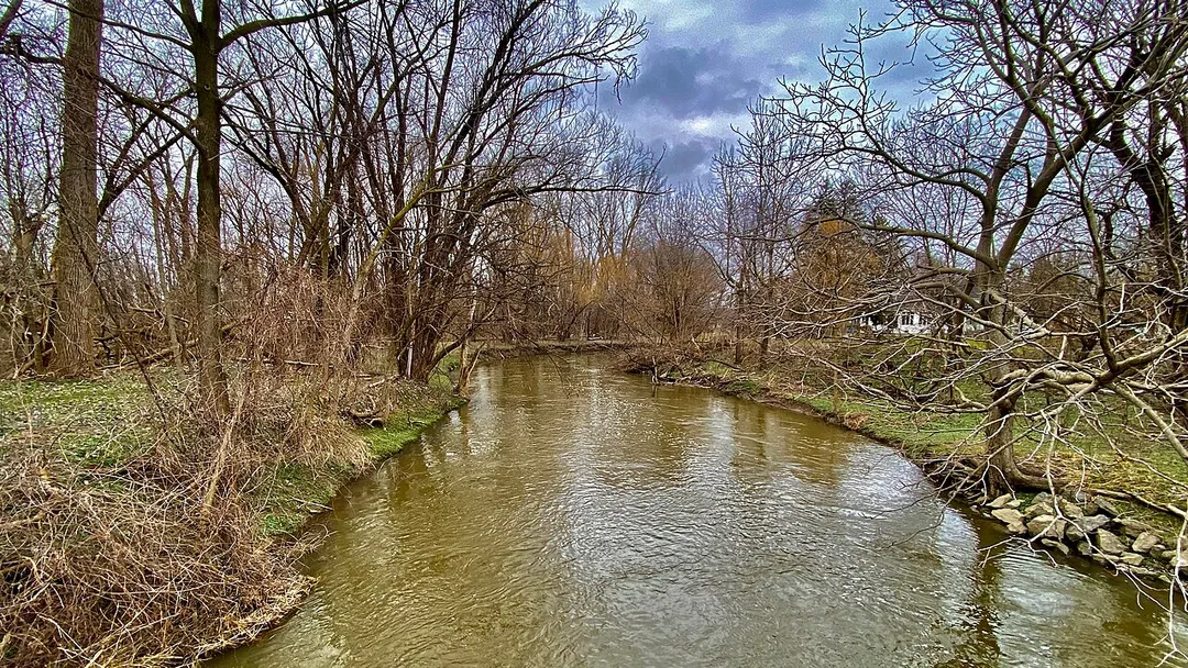 A view northward along Ellicott Creek from the Judith S. Chick Memorial Bridge near the east end of the Ellicott Creek Trailway in Amherst, New York. Chick (1942-2015) made a name for herself in the wake of a disastrous flood in February 1985 as founder of Concerned Citizens for Ellicott Creek Flood Control, an effort that culminated in a trip to Washington, D.C. to personally urge Congress to pass the namesake legislation. The completion of the project in 1988 opened the doors to the construction of the 4.4-mile original portion of the Trailway, which extends in a northwesterly direction roughly parallel to Ellicott Creek (hence its name) from Ellicott Creek Trailway Park on North Forest Road, passing through the North Campus of the University at Buffalo and the sprawling Audubon Industrial Park before ending at Ellicott Creek Park in nearby Tonawanda. A southward extension of the path, leading to the Audubon Recreation Complex on Amherst Manor Road, added 2.2 miles to the total length when it opened in May 2000.