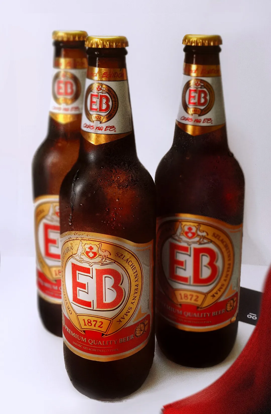 Three frosted bottles of Polish EB beer with labels.