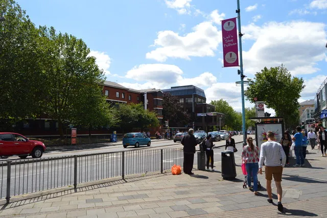A244, High Street, Feltham. The two buildings are New Chapel Square which has a central green and is social housing. The second building is commercial, Mercury House. The railway station is behind the camera a short way along Bedfont Lane or its High Street front (arrivals from London) is to the left