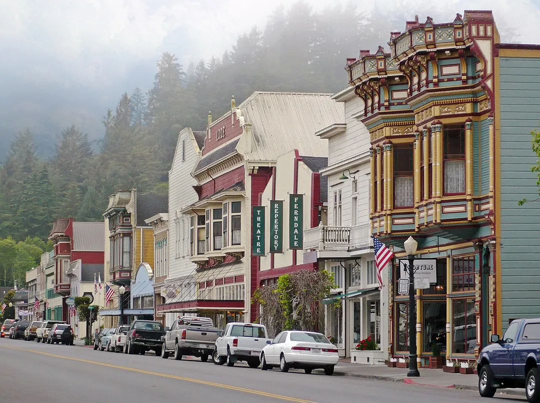 It shows the well-preserved Victorian architecture in the Main Street Historic District in Ferndale, California.
First visible polychrome building with flag is 475 Main Street, then 455 Main, and the Ferndale Repertory Theater at 441-451 Main.  This image was taken at the request of Ferndale Chamber of Commerce and used on a brochure published by the Chamber in 2015.