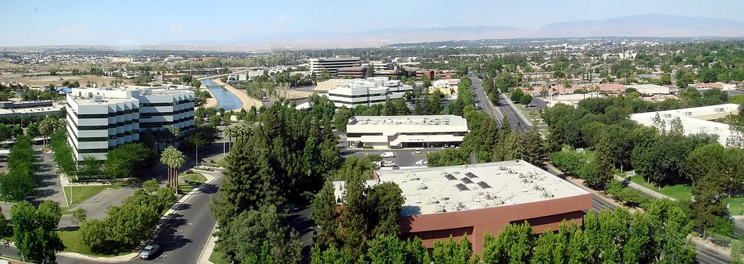 A panoramic view of Bakersfield, California, taken from Stockdale Tower, the tallest building in the city, facing east/northeast.  The office buildings in the foreground make up a mini financial district and regional offices for many oil companies that operate in the region; the major street to their right is California Avenue.  Towards the upper right is downtown Bakersfield, marked by the black-with-white-roof Truxton Tower (the 2nd tallest building in the city).  The area rising in the background-right is East Bakersfield.  The mountain range is the background are the Greenhorn Mountains.