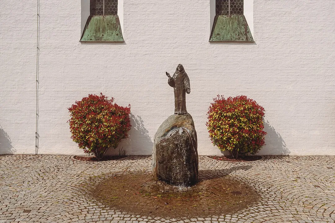A fountain in front of the church St. Benedikt in Gauting.