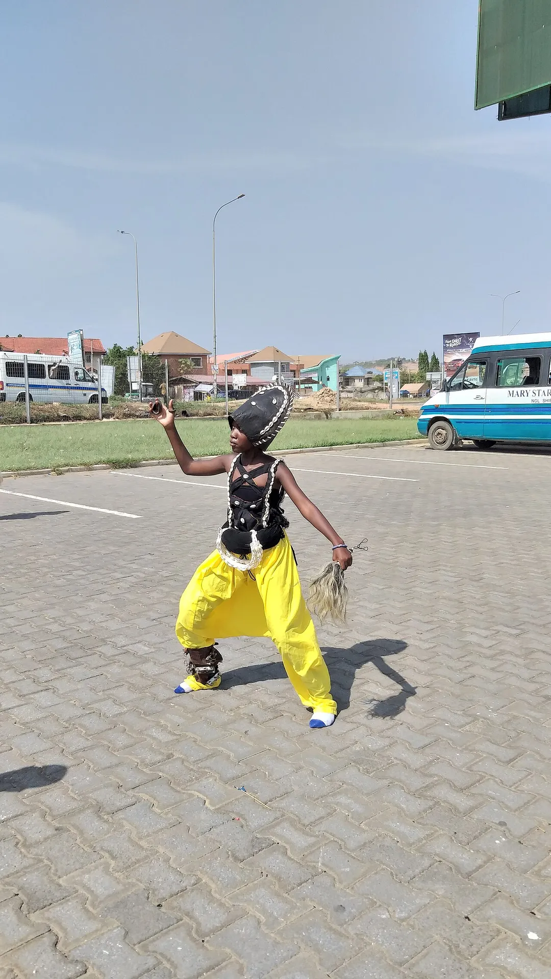 A traditionally dressed dancer holding an animal tail and calling for attention.