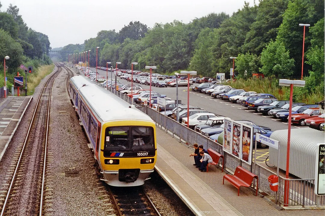 Gerrards Cross station, 1994.
View NW from the footbridge, towards Prins Risborough etc.: ex-GW&amp;GC Joint Railway, Paddington/Marylebone - High Wycombe - Princes Risborough - Banbury, Birmingham etc. (GW)/Leicester - Sheffield (GC). The ex-GC main line was closed 5/9/66. From March 1967, following the electrification of the WCML from Euston, the Paddington - Birmingham services were cut back progressively, then Birmingham trains were diverted via Oxford until 1980. Since then direct London - Banbury - Birmingham (Moor Street) services have run only to/from Marylebone. Until c. 1970 there were Fast lines between the Platform lines. The new Tesco Tunnel over the station would be largely behind the photographer here. The Up train is a Class 165 'Turbo' DMU on a Birmingham (Moor Street) - Marylebone service.