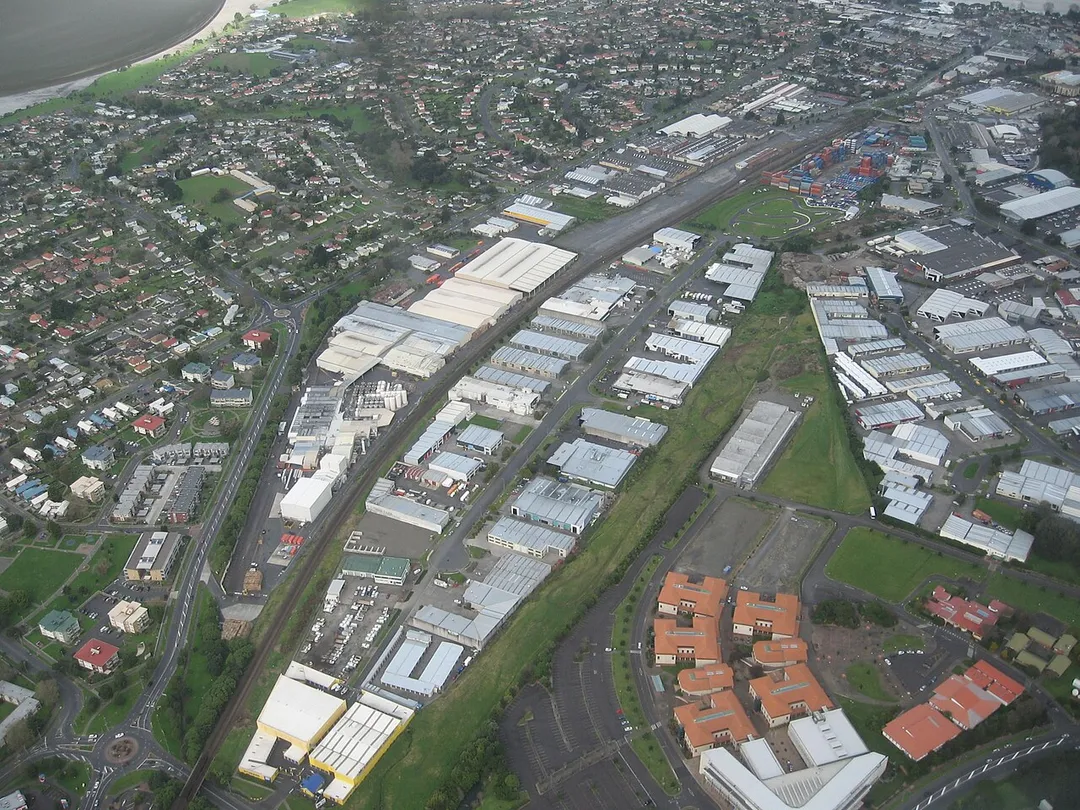 The Eastern Line from Glen Innes (lower left corner) towards the former Tamaki train station (upper right hand corner - the widened area to the left (east) of the colourful container stacks) and finally to Panmure (out of the picture). Seen from a plane, looking southeast over Auckland, New Zealand.