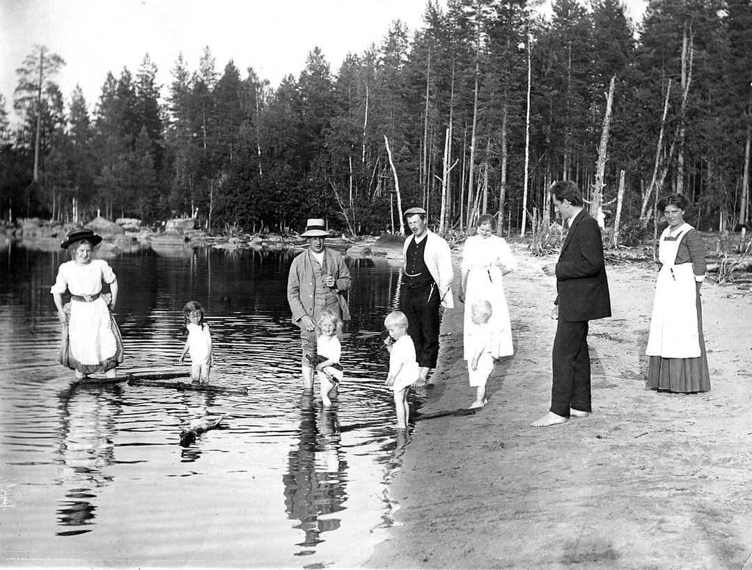 Photograph of the Finnish politician Väinö Hakkila (1882–1958), standing in the water with white hat on, with his family.