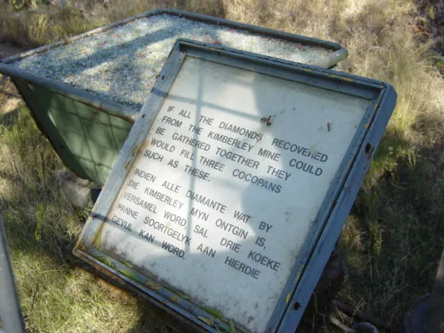 A sign next to the Big Hole, reading "If all the diamonds recovered from the Kimberley Mine could be gathered together they would fill three cocopans such as these".