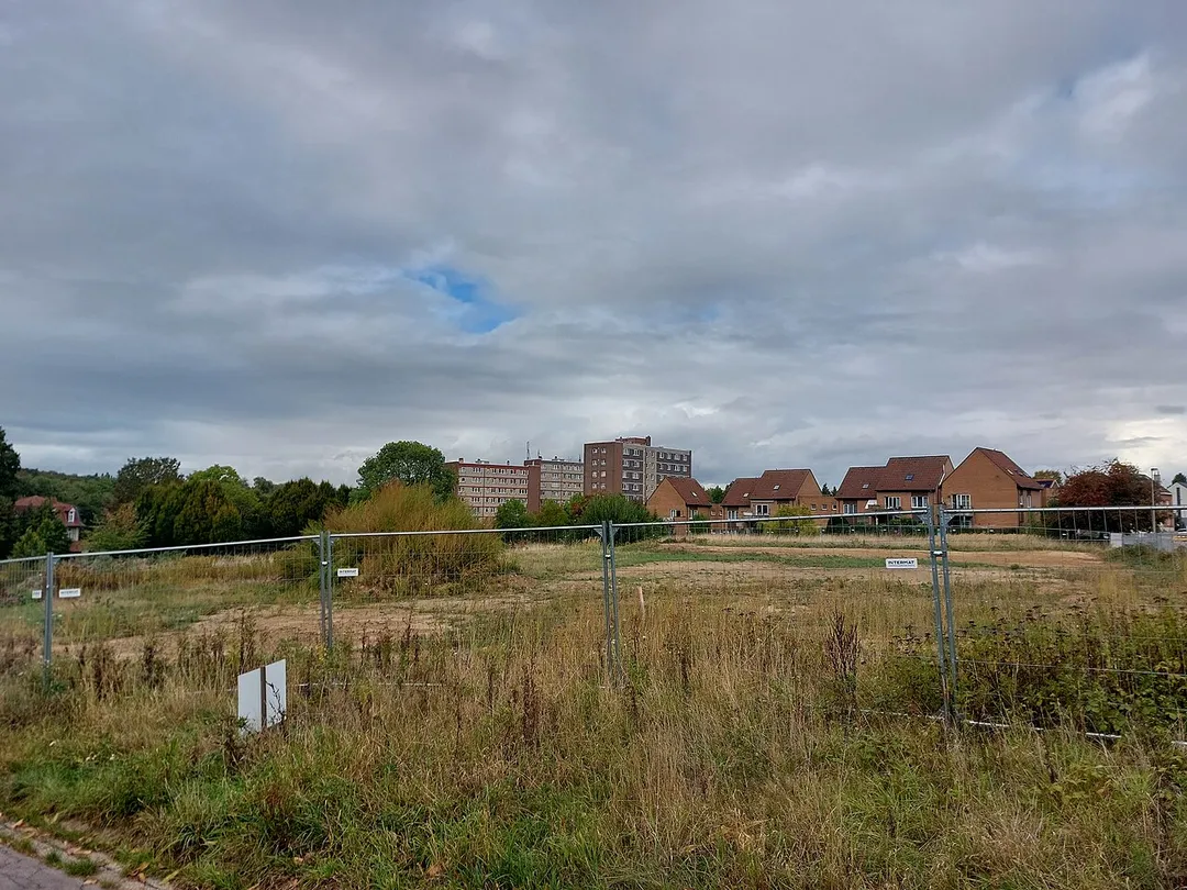 View of social housing estates in southern Kraainem town with a fenced wasteland in the foreground.