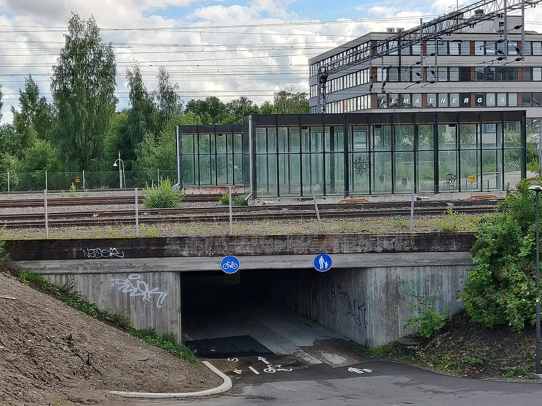A pedestrian underpass, railway and buildings in the background.