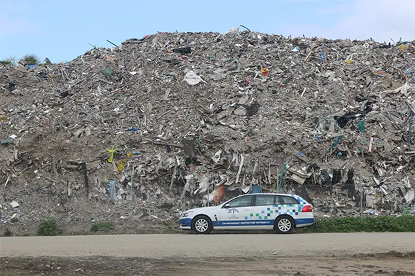 EPA car in front of stockpiles of waste at a recycling facility in Lara, Victoria, Australia