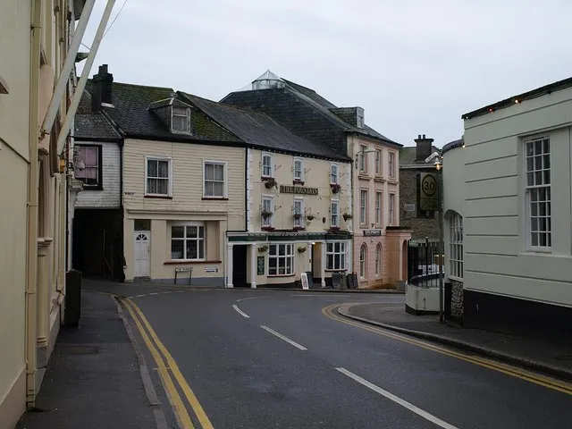Fountain Hotel, Cornwall The irregularly-shaped square called The Parade is the site of most of Liskeard's grander town houses. This row is at the northern side, running into Barras Place (left). 
"Mid C19 remodelling of probable C18 house. Stucco on studwork; dry Delabole slate roof" - the full description of the hotel is at https://historicengland.org.uk/listing/the-list/list-entry/1024986 . The part slate-hung house to its left is also listed, and also part of the hotel - see https://historicengland.org.uk/listing/the-list/list-entry/1203196 . For number 2, The Parade, the taller building to the right, see https://historicengland.org.uk/listing/the-list/list-entry/1355173 - the building has been repainted since that photo was taken.

View from West Street.