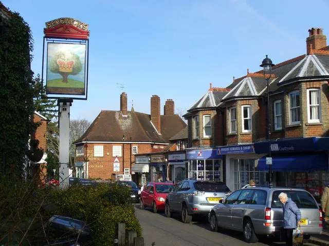 High Street Downtown Great Bookham with pubs and shops lining the busy High Street. The Royal Oak sign still carries the name of a former brewery - Sedgwick's of Watford.