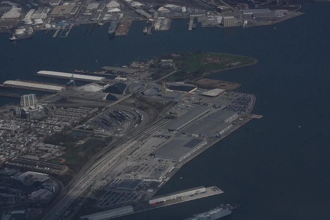 Oblique view of the peninsula of Locust Point, Baltimore, including Fort McHenry.  The west entrance of the Fort McHenry Tunnel (Interstate 95) is visible, as is Latrobe Park.  The water bodies are branches of the Patapsco River.  The land along the top of the photo is Lazaretto Point and includes Rukert Terminal.