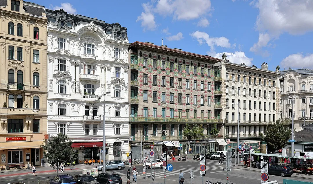Die Linke Wienzeile auf der Höhe der Kettenbrücke(ngasse) im 6. Wiener Gemeindebezirk Mariahilf mit dem „Majolikahaus“ von Otto Wagner im Bildzentrum.Ganz links Haus Nr.44, Wohnhaus des Heldentenors Hermann Winkelmann (1849–1912), anschließend Haus Nr. 42, ein reich gegliedertes historistisches Wohn- und Geschäftshaus, das von 1896 bis 1897 nach Plänen von Rudolf Kmunke errichtet wurde. Im Anschluss Haus Nr. 40, auch „Majolikahaus“ bezeichnet, ein Miethaus, das von Otto Wagner 1898/1899 errichtet wurde und das Eckhaus „Köstlergasse“ mit vergoldetem secessionistischem Dekor, wiederum ein von Otto Wagner 1898/1899 errichtetes Haus und ganz rechts Haus Nr. 36, ein monumentales späthistoristisches Mietpalais, erbaut 1897 nach Plänen von Franz Ritter von Neumann. Rechts im Vordergrund die Kettenbrücke und der Naschmarkt.