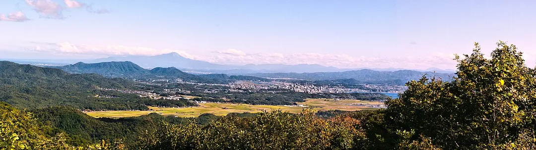Matsue area seen from Mt.Asahi. The city of Matsue can be seen in the center of the photo. To the left are Mt.Dake and Mt.Wakura, and further back is Mt. Daisen(Tottori Prefecture). The body of water to the right of Matsue City is Lake Shinji.