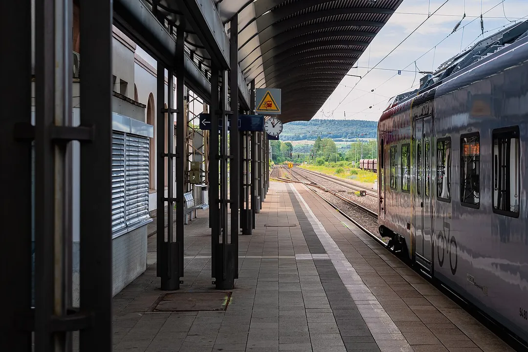 A platform of the train station Merzig (Saar) with standing regional train. The clock at the plattform shows the time 11:07.