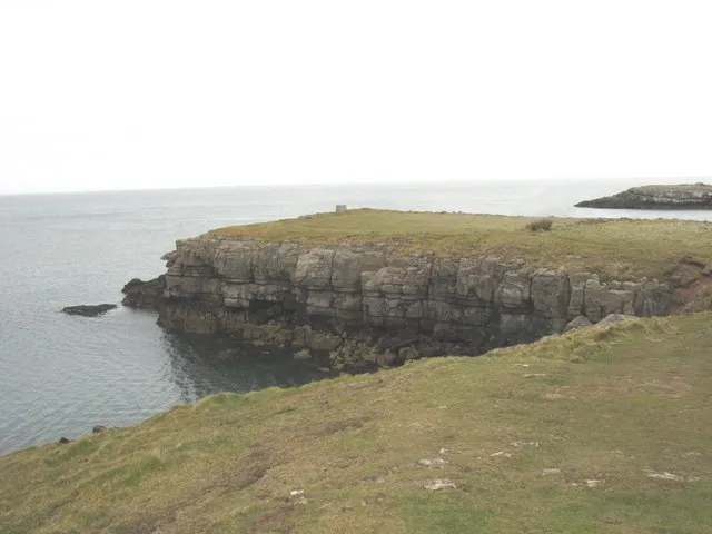 View back to the headland and Ynys Moelfre The Hindlea monument - which is in the form of a seat and an ideal place for an alfresco lunch - is clearly visible at the tip of the headland. The coastal path follows the edge of the cove in the foreground.