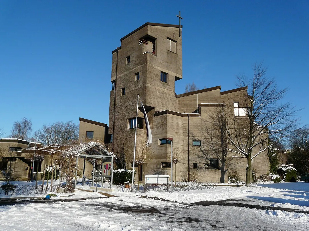 Die Abbildung stellt die Friedenskirche Baumberg in der Ansicht von Süden dar. Durch die fehlende Belaubung der Kletterpflanzen ist die äußere Struktur zu dieser Jahreszeit besser sichtbar.